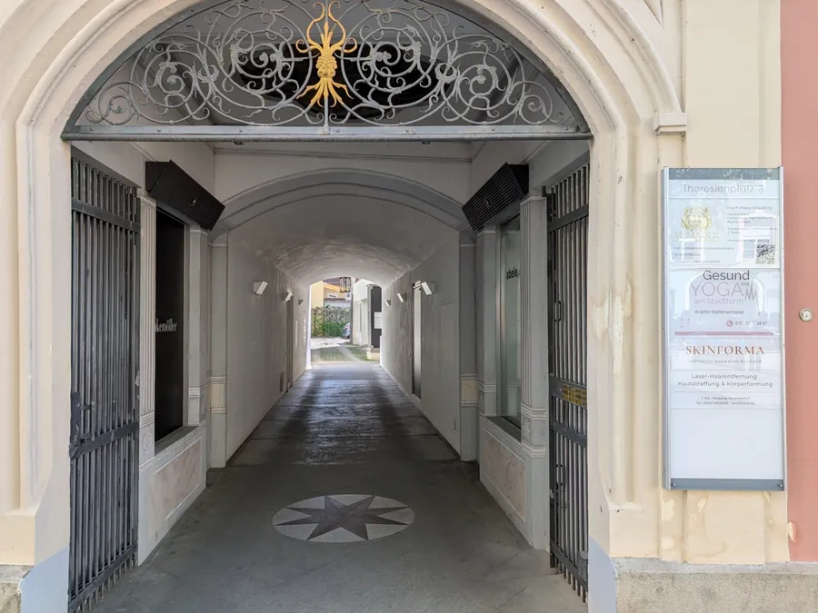 Blick durch den geöffneten Torbogen in den gewölbten Hausdurchgang, am Ende der Innenhof