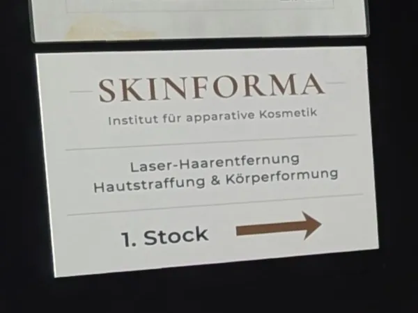 Schild im Treppenhaus: SKINFORMA, Institut für apparative Kosmetik, Laser-Haarentfernung, Hautstraffung & Körperformung, 1. Stock